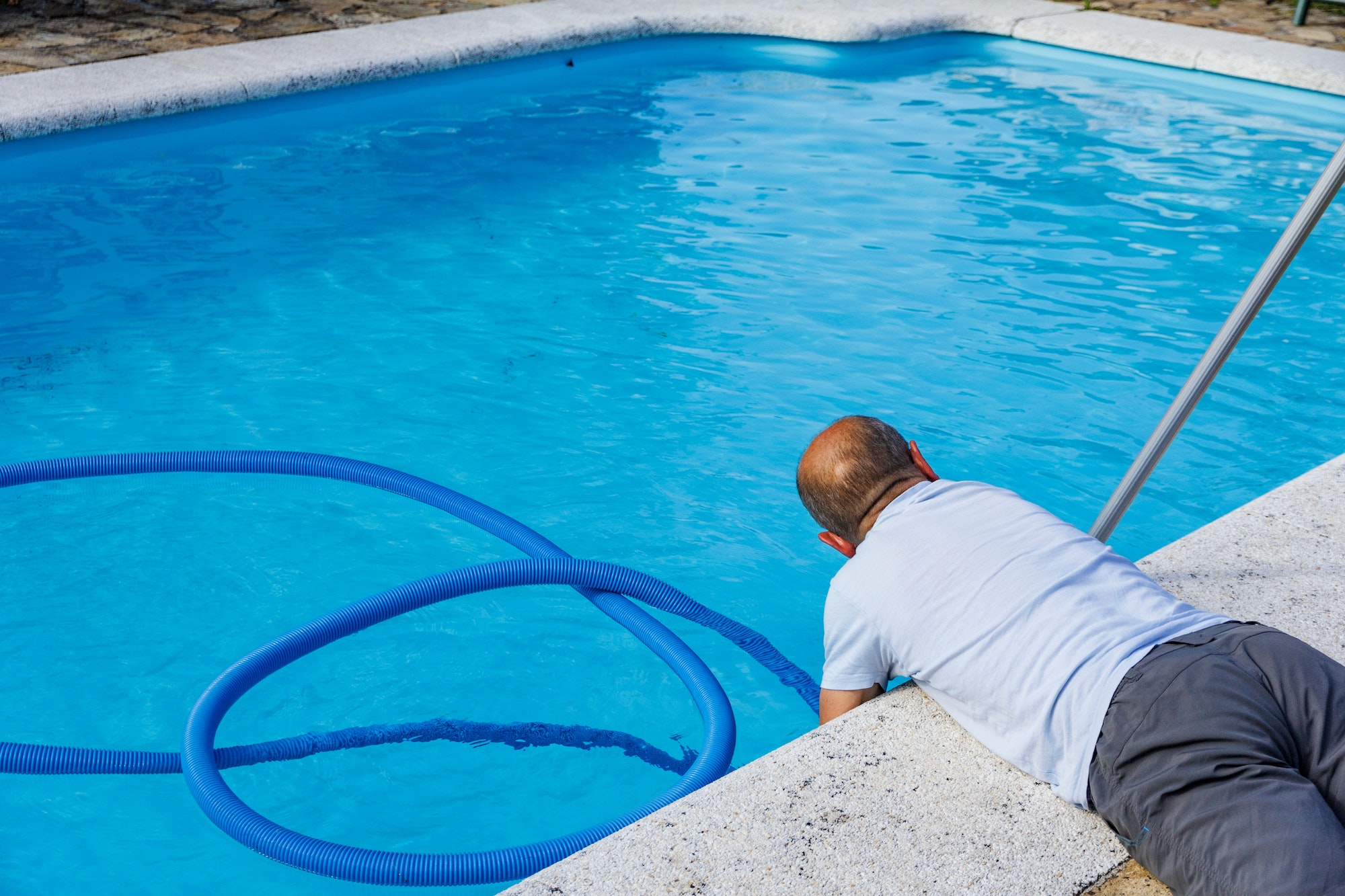 Man cleaning the pool at home, lying on the floor, doing chores, housework, household